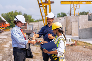 construction site meeting with two workers discussing project details while exchanging documents